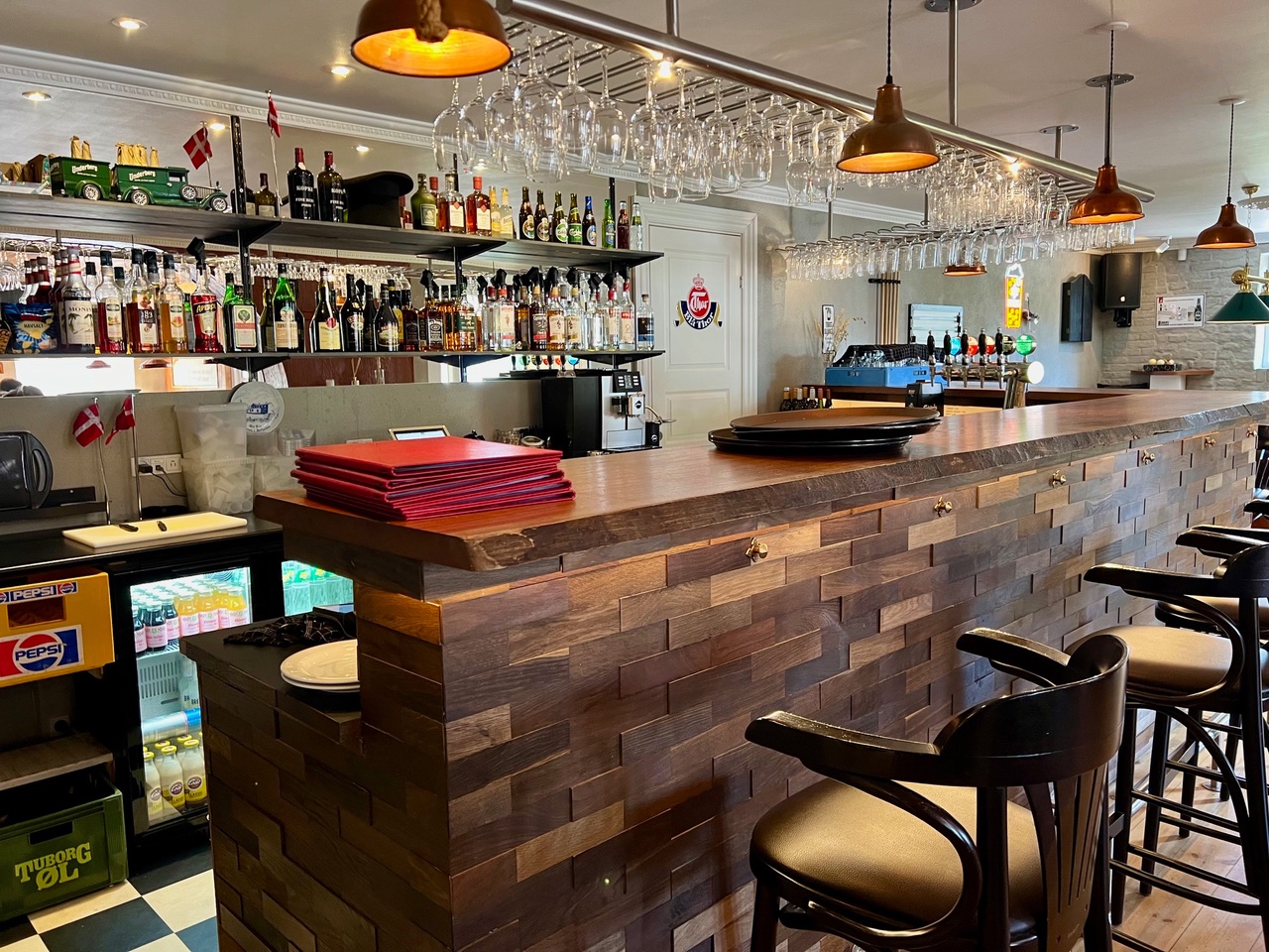 Hyggelig bar på Orø Kro & Hotel med træbar, flasker og hængende glas